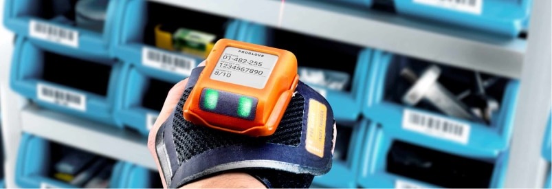 Préparation de commande : Appareil portable affichant des données sur le poignet, devant des bacs de rangement.