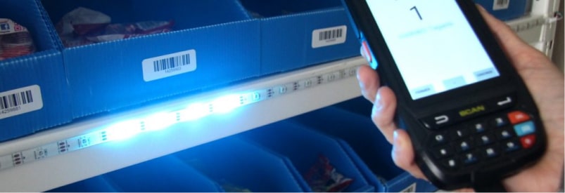 Solutions de préparation de commande : Scanner et étagères avec lumières LED bleues.