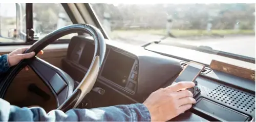 Conducteur utilisant un téléphone dans un fourgon. Solutions de gestion de flotte IoT.