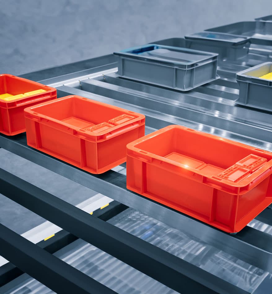 Casiers orange et gris sur convoyeur industriel. Tags durci RFID.