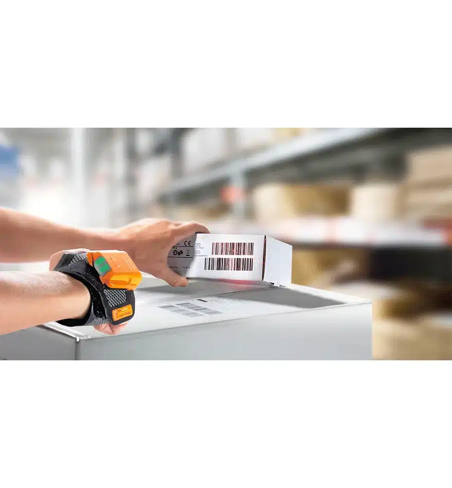 Scanner MARK 2 ProGlove au poignet scannant un code-barres sur un colis dans un entrepôt.