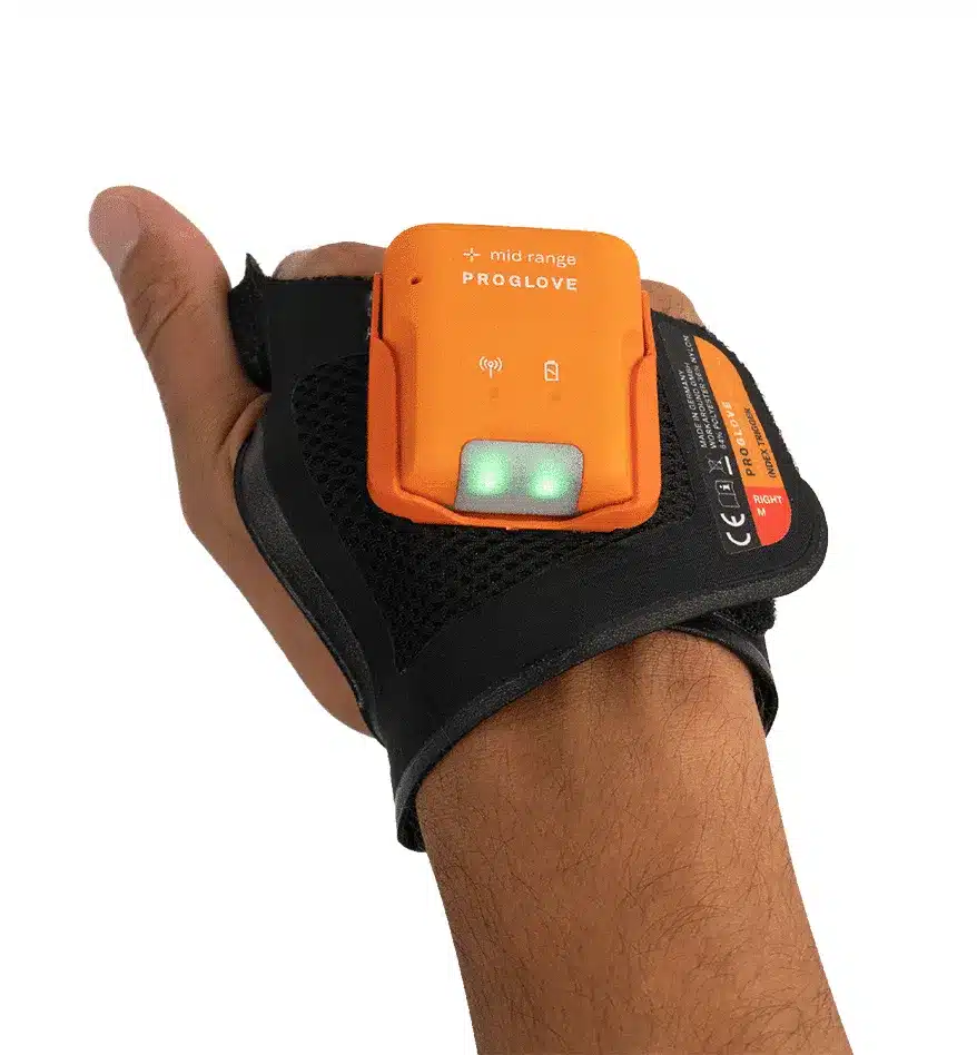Main tenant un scanner MARK 2 ProGlove orange fixé sur un gant noir. Scanner mains-libres ProGlove.