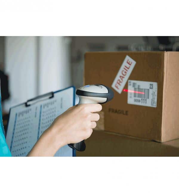 Scanner lisant un code-barres sur un carton étiqueté "FRAGILE". Étiquettes linerless en usage.