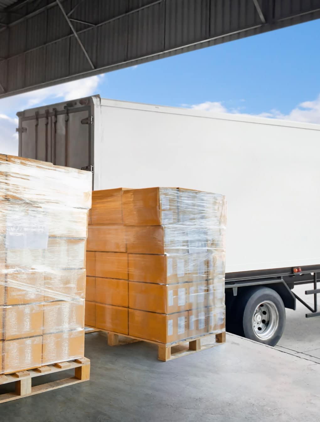 Palettes chargées devant un camion blanc. Solutions de gestion de flotte IoT.