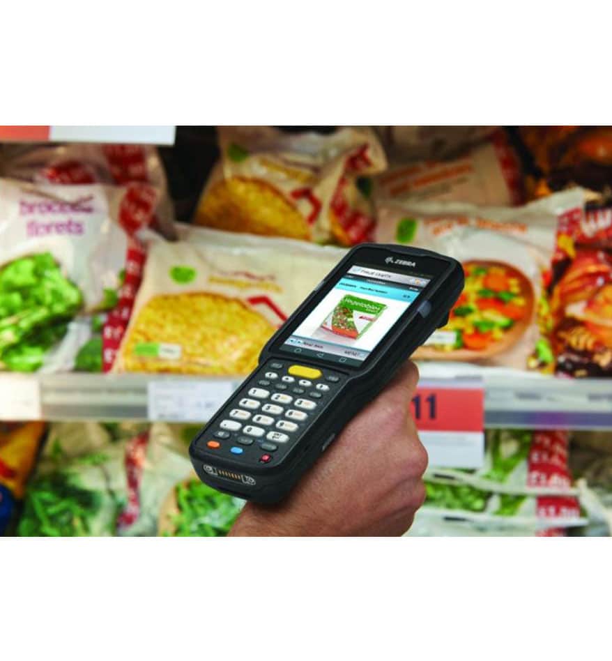 Terminal MC3300x Zebra utilisé pour scanner des produits alimentaires surgelés dans un supermarché.