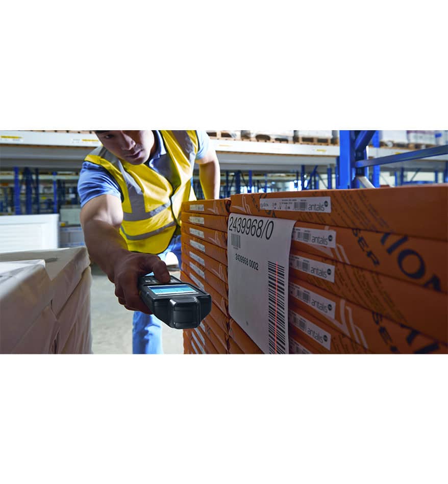 Employé scannant un code-barres sur un emballage avec un terminal MC3300x Zebra dans un entrepôt.