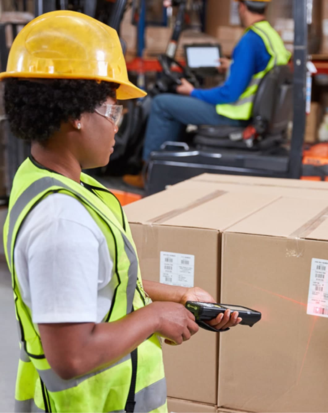 Employée scannant un code-barres sur une boîte dans un entrepôt. Solutions de traçabilité.