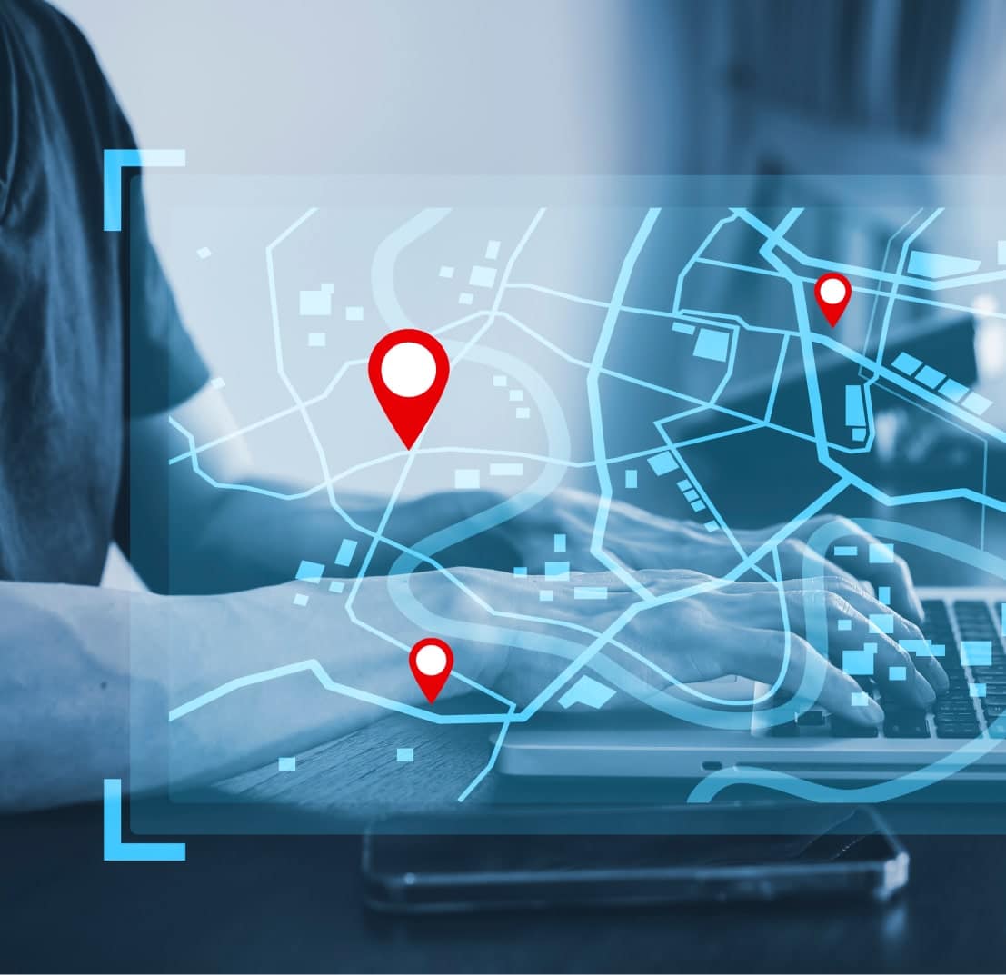 Personne utilisant un ordinateur portable avec une carte et des marqueurs d'emplacement. Solutions de gestion de flotte IoT.