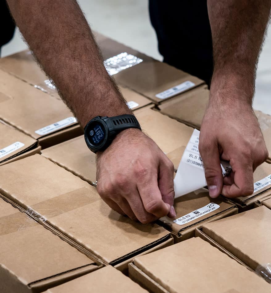 Homme collant des étiquettes RFID sur des boîtes. L'étiquette indique "SLS 62 2C".