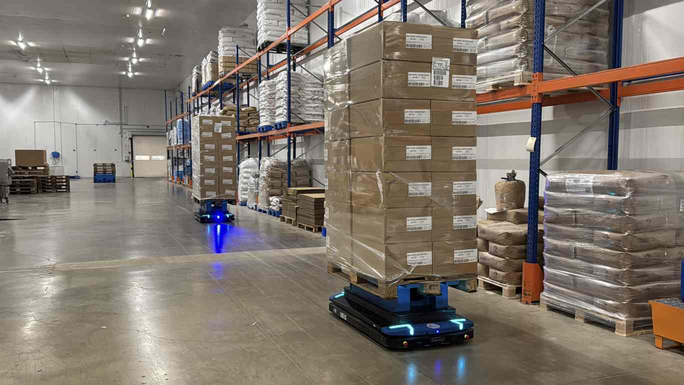AGV transportant des palettes dans un entrepôt Vandemoortele pour l'optimisation et l'automatisation.