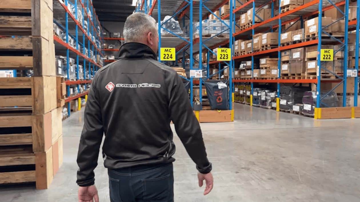 Homme dans un entrepôt automatisé avec des étagères remplies de marchandises. Automatisation de la chaîne de production Symta.