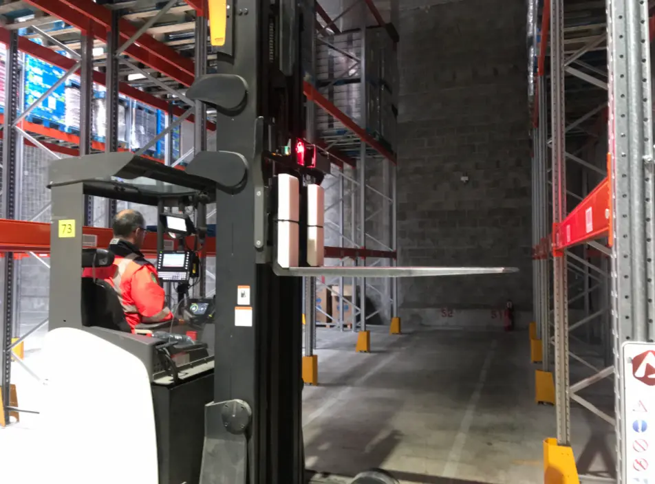Lecteur sur chariot élévateur à fourches dans un entrepôt. Solutions de suivi du transport possibles.