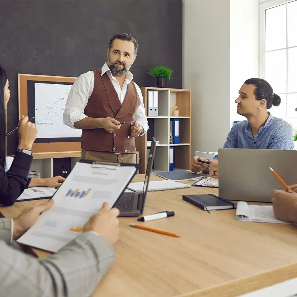 Homme présentant des formations certifiées à une équipe autour d'une table.