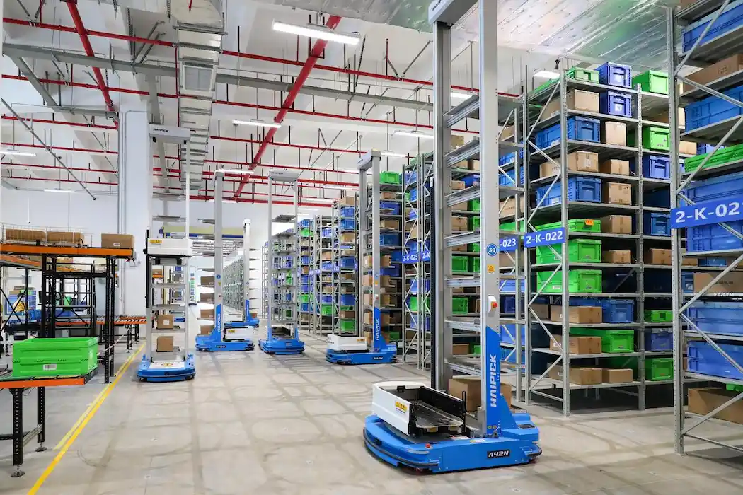 Entrepôt automatisé u0022pallet to personu0022 avec robots bleus déplaçant des marchandises.