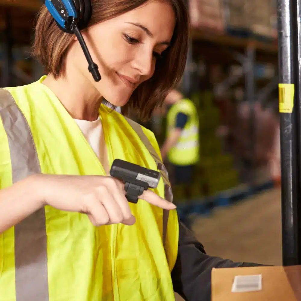 Employée d'entrepôt utilisant un scanner de doigt. Location matériel durci pour PDA et terminaux mobiles.