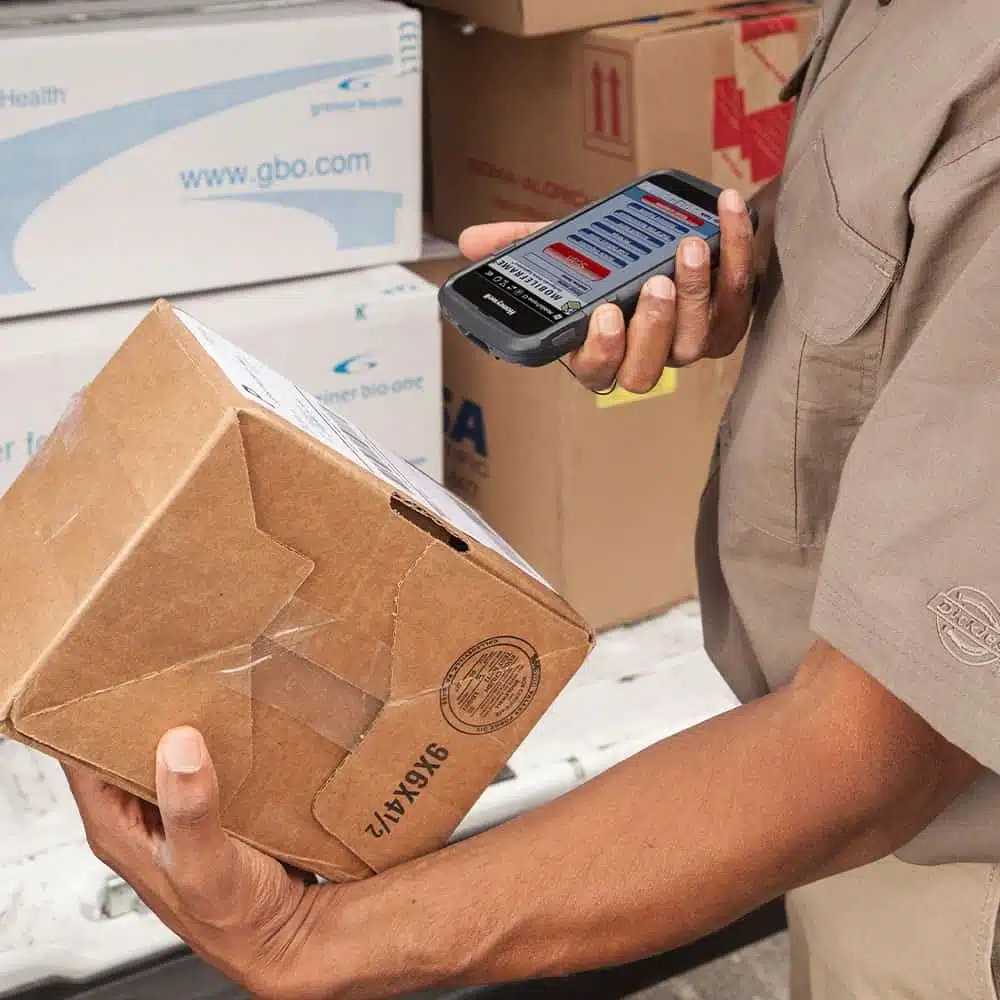 Employé scannant un colis avec un terminal mobile. Location matériel.