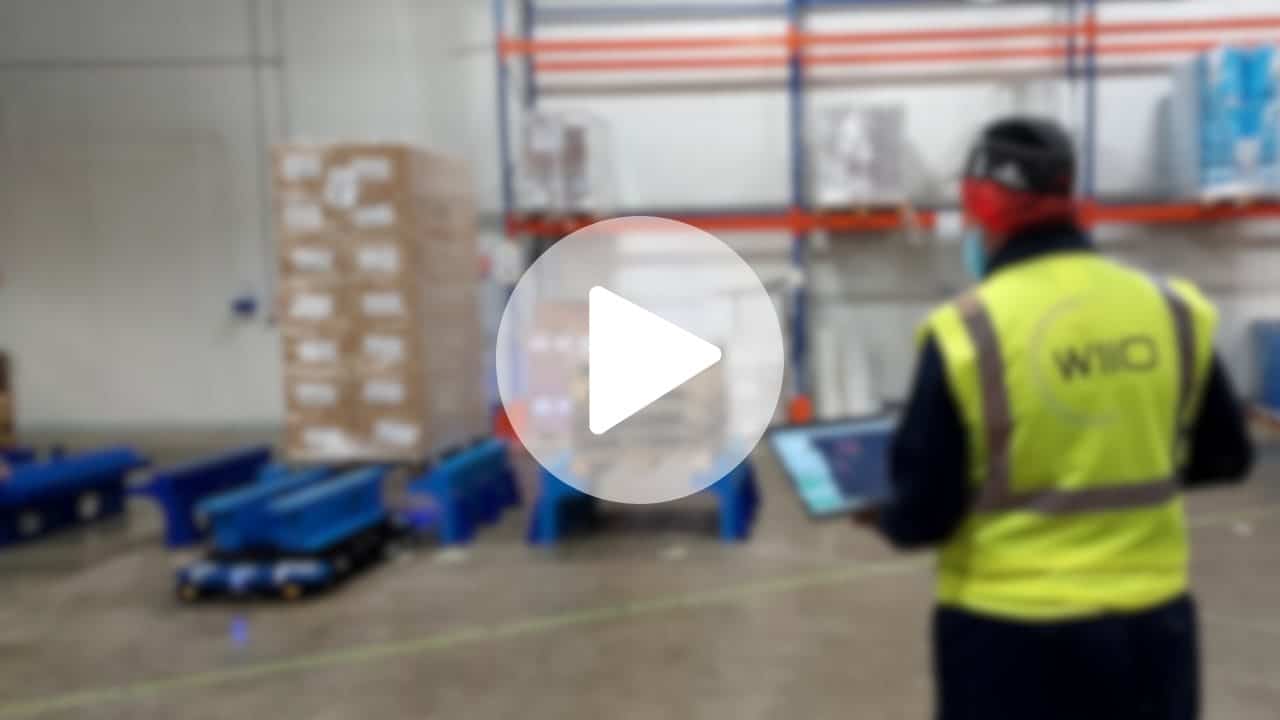 Automatisation Vandemoortele : employé utilisant une tablette près de robots de palettes. Optimisation et localisation.
