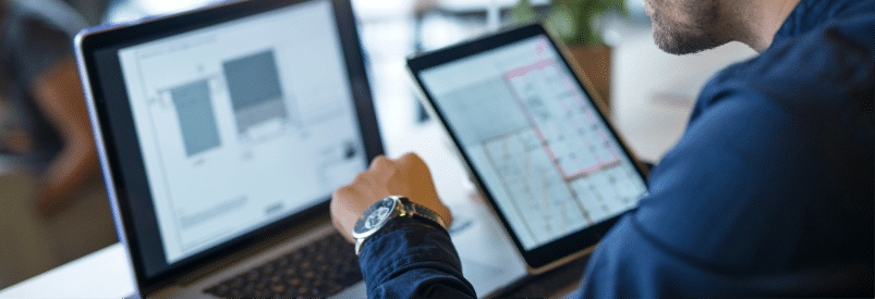 Homme travaillant sur un ordinateur portable et une tablette avec des graphiques.