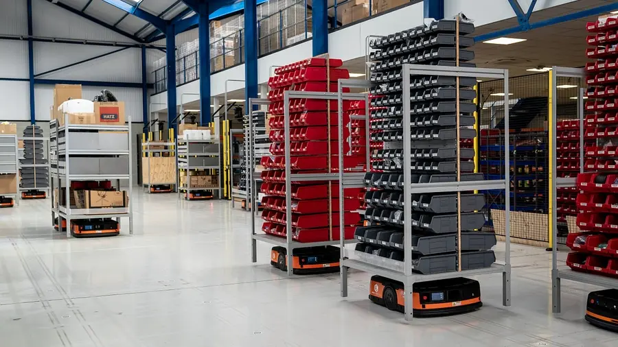 Système "pallet to person" avec étagères mobiles automatisées dans un entrepôt.