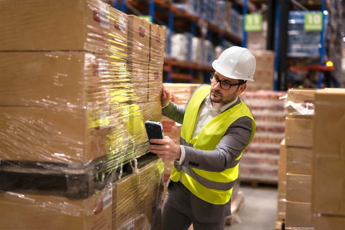 operateur qui prend en photo un carton dans un entrepot